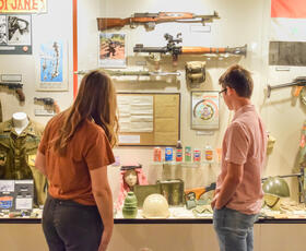 Two visitors view a display of military uniforms, weapons and memorabilia inside the North Louisiana Military Museum.