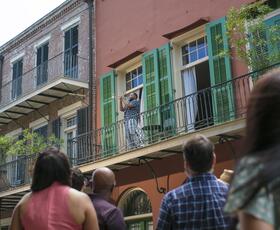 Visitors watch as a trumpeter performs on a balcony in the French Quarter.