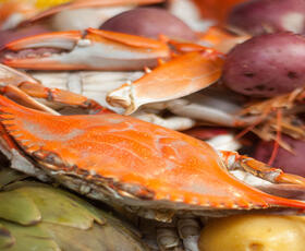 A Louisiana seafood boil, featuring crab, corn on the cob, red and yellow potatoes, and artichokes.