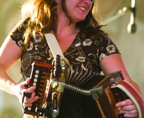 A woman playing an accordion on stage at the Festival Acadiens et Creoles in Lafayette.