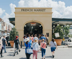A large archway making the entrance to the French Market in New Orleans, Louisiana, surrounded by people shopping.