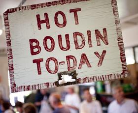 A sign reading “Hot Boudin To-Day” in red paint at Johnson's Boucanière in Lafayette.