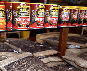Bags of Conrad Mill Rice and bottles of Cajun seasoning by Konriko Spices in a dimly lit shop.