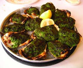 Oysters Rockefeller, featuring oysters on the half shell topped with a bright green sauce and broiled to a perfect char.
