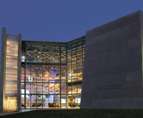 A large building with glass windows, glowing during the evening in New Orleans, Louisiana.