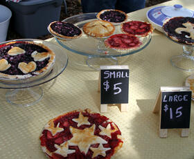 Table with fruit pies of varying sizes and price signs for small and large pies.