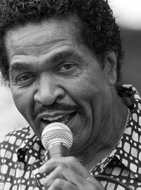 A close up of Bobby Rush holding a microphone and crooning to the camera