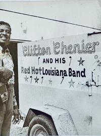 Clifton Chenier poses with an accordion in front of a vehicle with Clifton Chenier and his red hot Louisiana Band on it