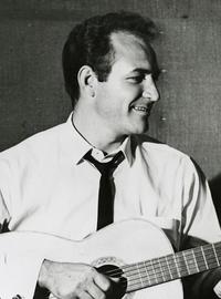 Fred Carter Jr. strums a guitar and smiles off to the viewer's right