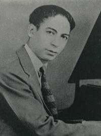 Jelly Roll looks at the camera while he plays the piano in a black-and-white picture