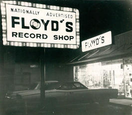 A black and white image of Floyd's lit-up sign and entrance