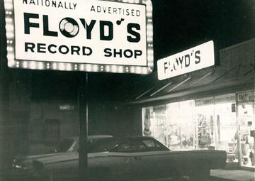 A black and white image of Floyd's lit-up sign and entrance