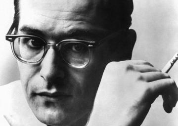 A portrait Bill Evans, wearing glasses and holding a cigarette