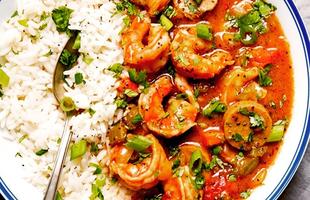 A white, blue-rimmed bowl holds rice and crawfish.