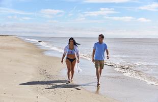 A man and woman walk along the shore of Holly Beach in Louisiana.