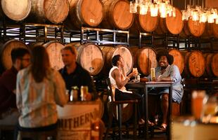 people at a brewery with barrels in the background