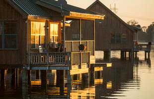 The wooden cabins on the water at Poverty Point Reservoir State Park are lit during golden hour.